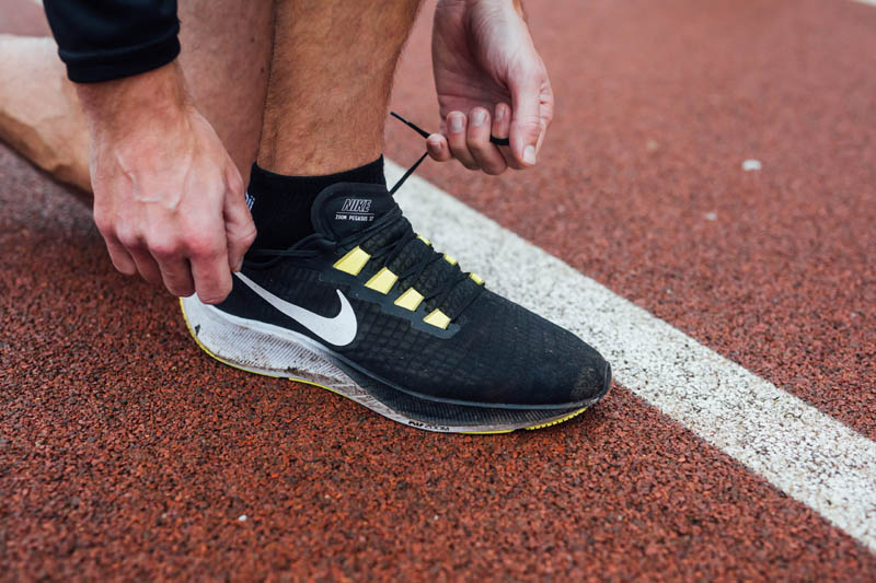 Image of Conor tying shoelaces on running track 