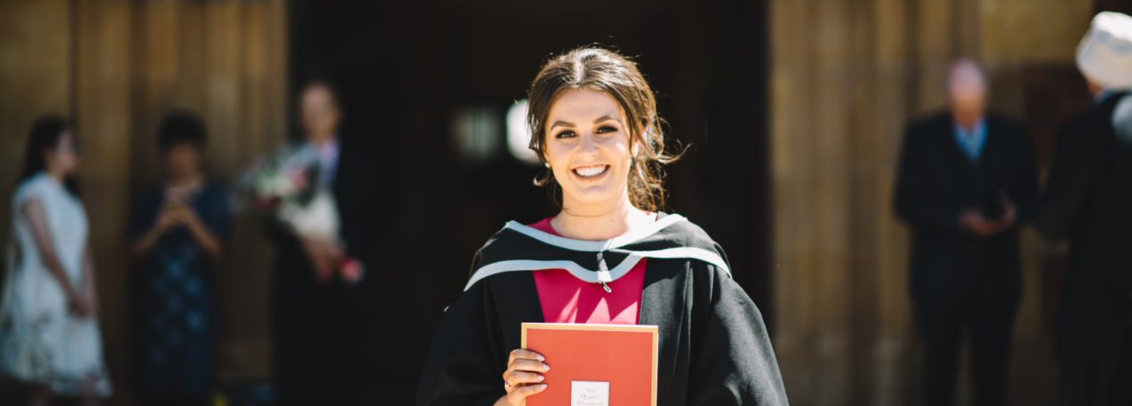 female graduate holding University degree in graduation gown