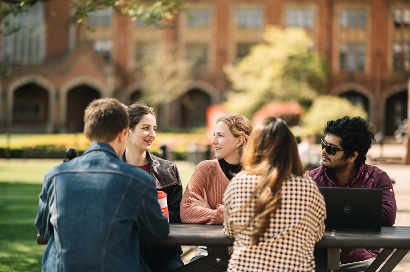 Students sitting at a bench in Queen's quadrangle