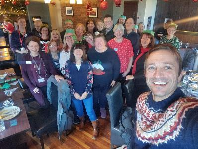 Image shows members of the Carers Network posing for a selfie at their 2022 Christmas Lunch in Ryan's, Belfast.