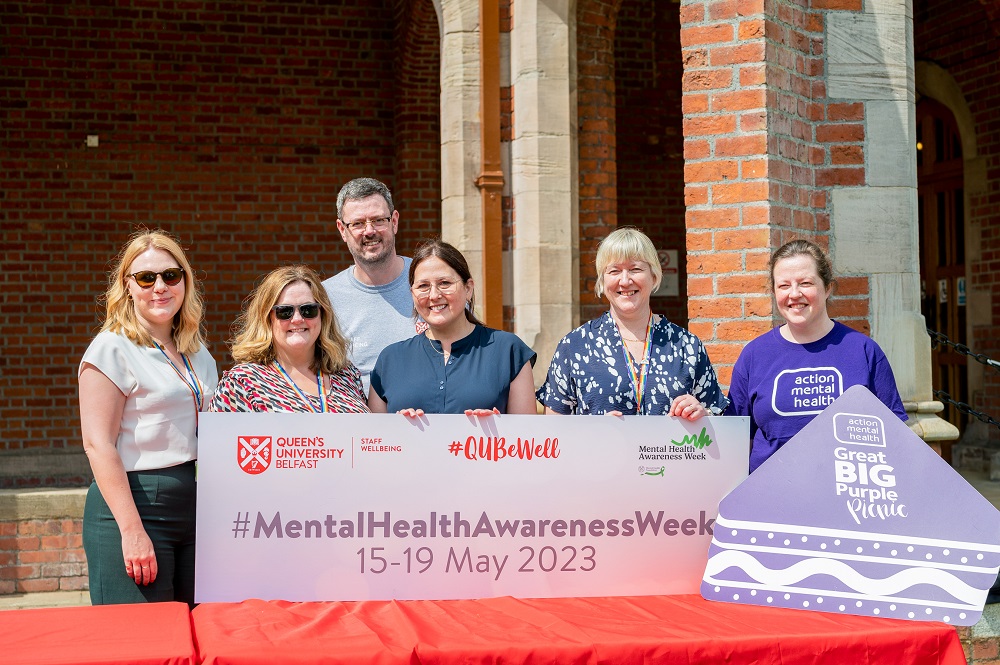 organising staff from Staff Wellbeing and Action Mental Health holding a banner Mental Health Awareness Week 2023 in the quad