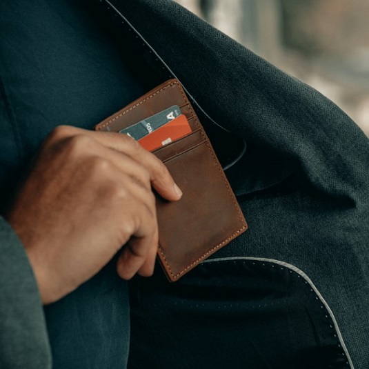 person putting wallet with credit cards in inside coat pocket