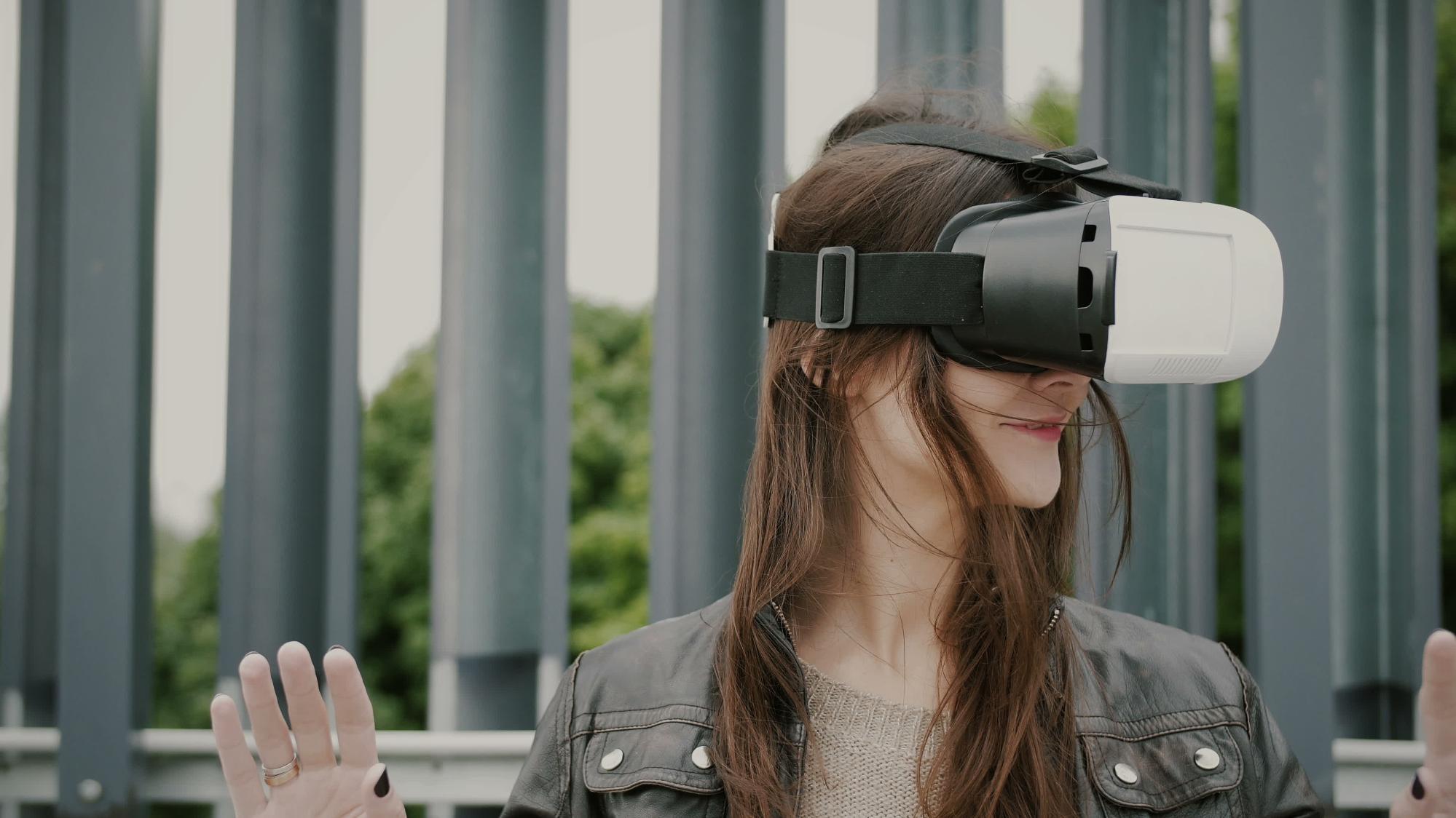 A woman wears a VR headset with a fence in the background