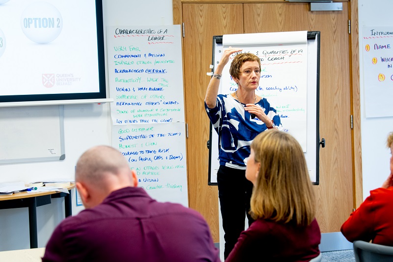 Dr Louise O'Meara from the Leadership Institute at Queen's University Belfast taking a training session in front of flip chart and screen projection