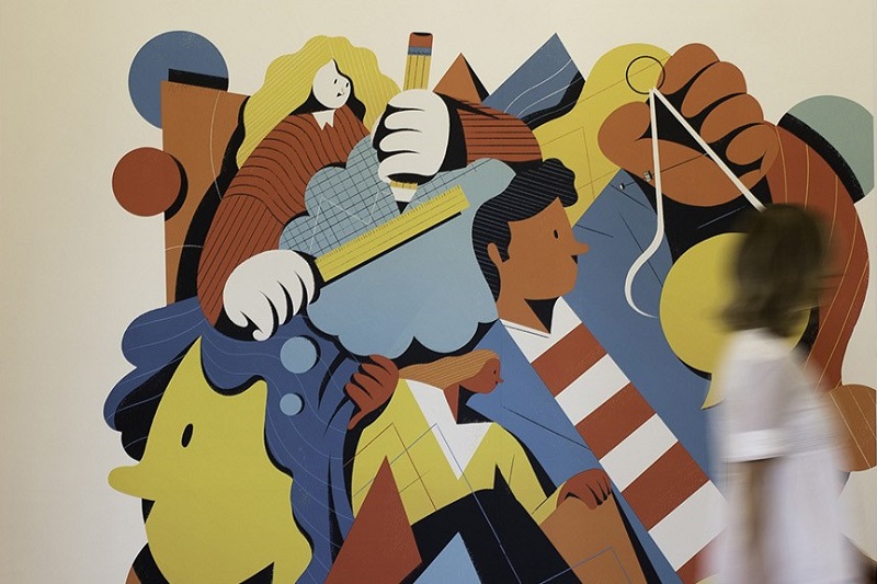 blurred woman walking past a piece of abstract wall art