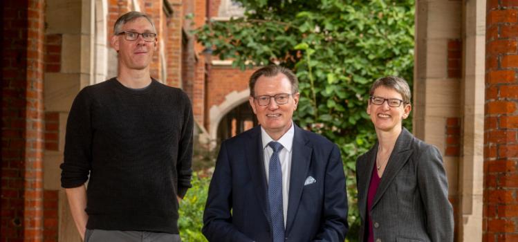 three staff members standing under the Queen's University Belfast clocktower: left to right: James Vincent, Professor Sir Ian Greer, Dr Sandra Scott-Hayward