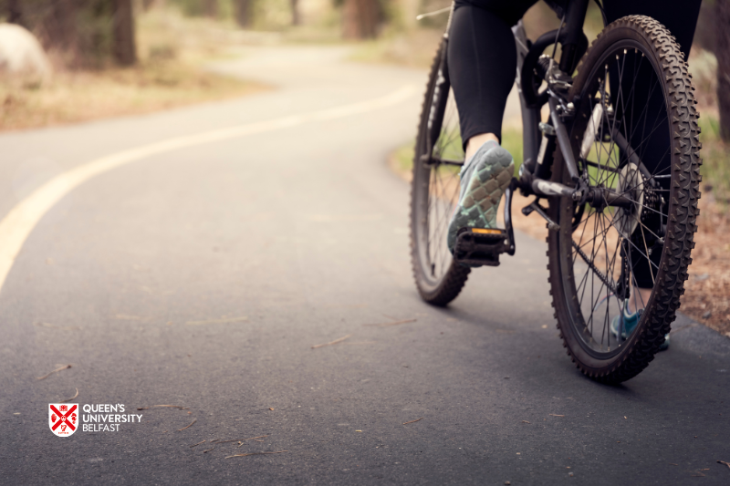 lower part of a bicycle on an empty road - image includes Queen's University Belfast logo