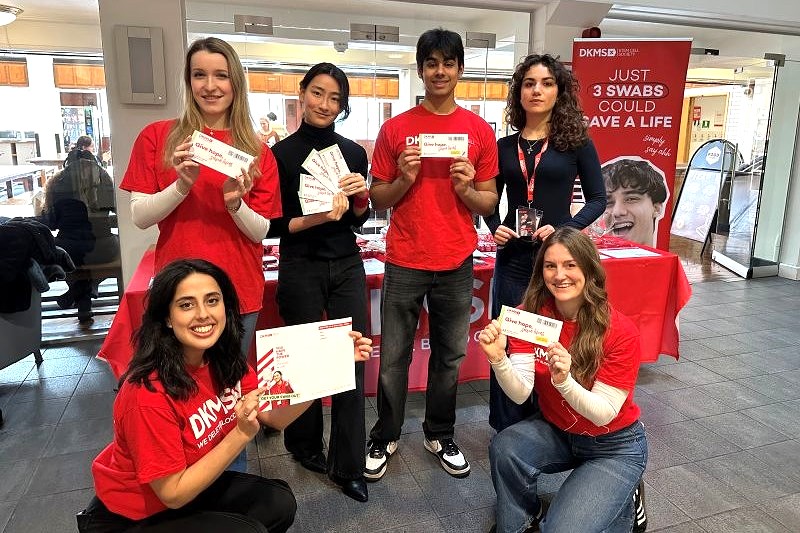 group of young adults wearing branded red t-shirts and holding marketing collateral in an indoor space