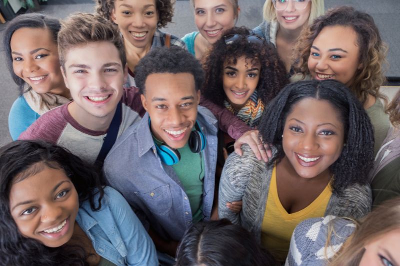 close-up aerial shot of a mixed group of young people or students smiling up to camera