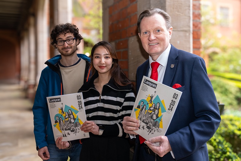 Vice-Chancellor Professor Sir Ian Greer with students Jesselyn Angka and Deivydas Sakys holding copies of Lanyon magazine summer 2024 in the quadrangle cloisters, Queen's University Belfast