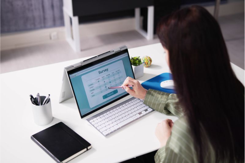 woman in clean office seated at desk using tablet to work on an online survey