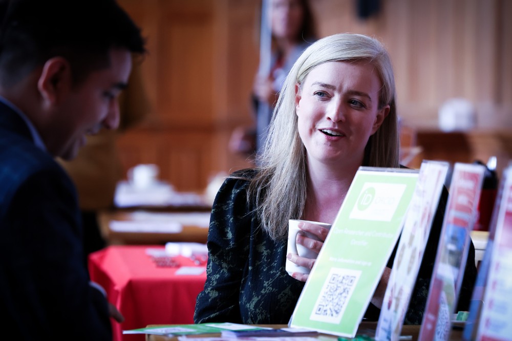 seated woman smiling while chatting to another indoor event attendee
