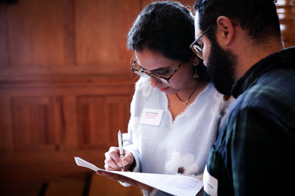 woman writing something down while listening to a man standing next to her