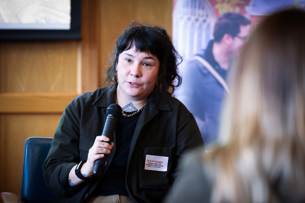 seated woman speaking to a room of event attendees