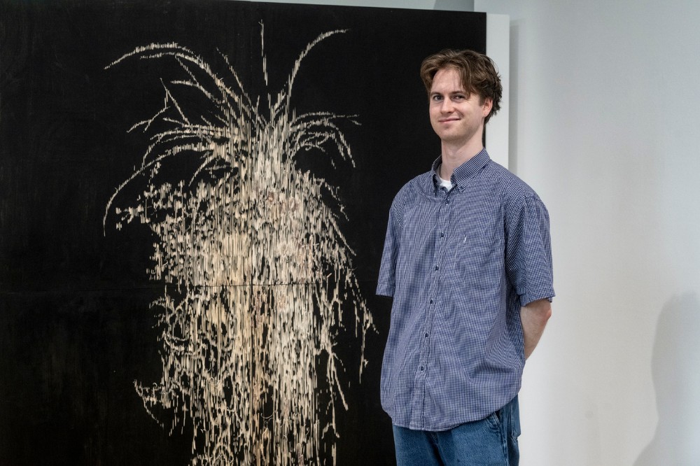 young man posing beside an artwork in a gallery