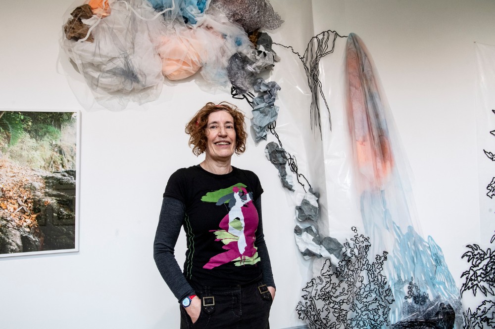 smiling woman standing in front of an artwork in an art gallery