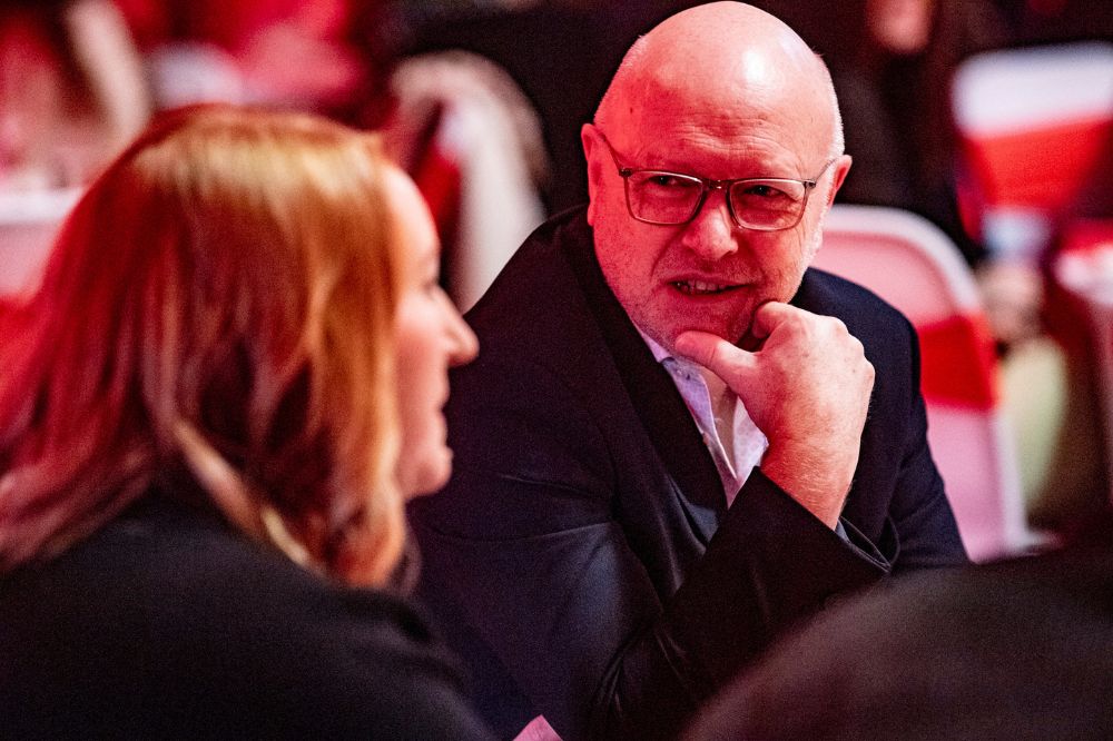 man and woman chatting at a table at an indoor event