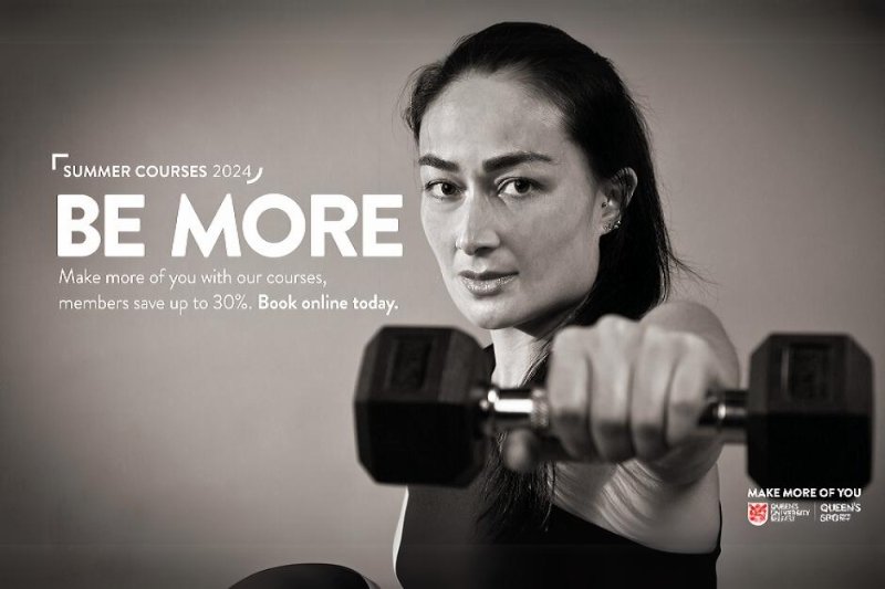 Young, serious-looking, sporty woman looking to camera and holding up a dumbell in a gym. Image includes wording 'Summer courses 2024 / Be More / Make more of you with our courses, members save up to 30%. Book online today.'