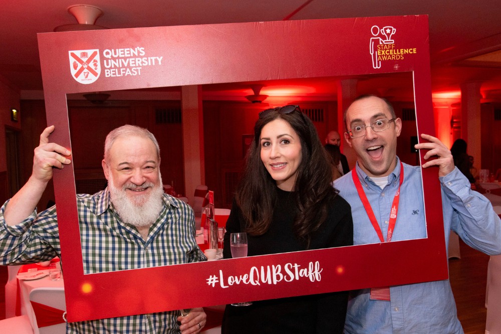 two men and a woman smiling and posing in an Instagram photo frame cutout